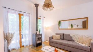 Una sala de estar moderna con un sofá gris, una mesa de centro blanca, una chimenea y un espejo grande en la pared.