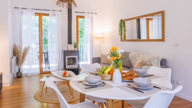 Una sala de estar moderna con comedor, chimenea y un espejo grande en la pared.