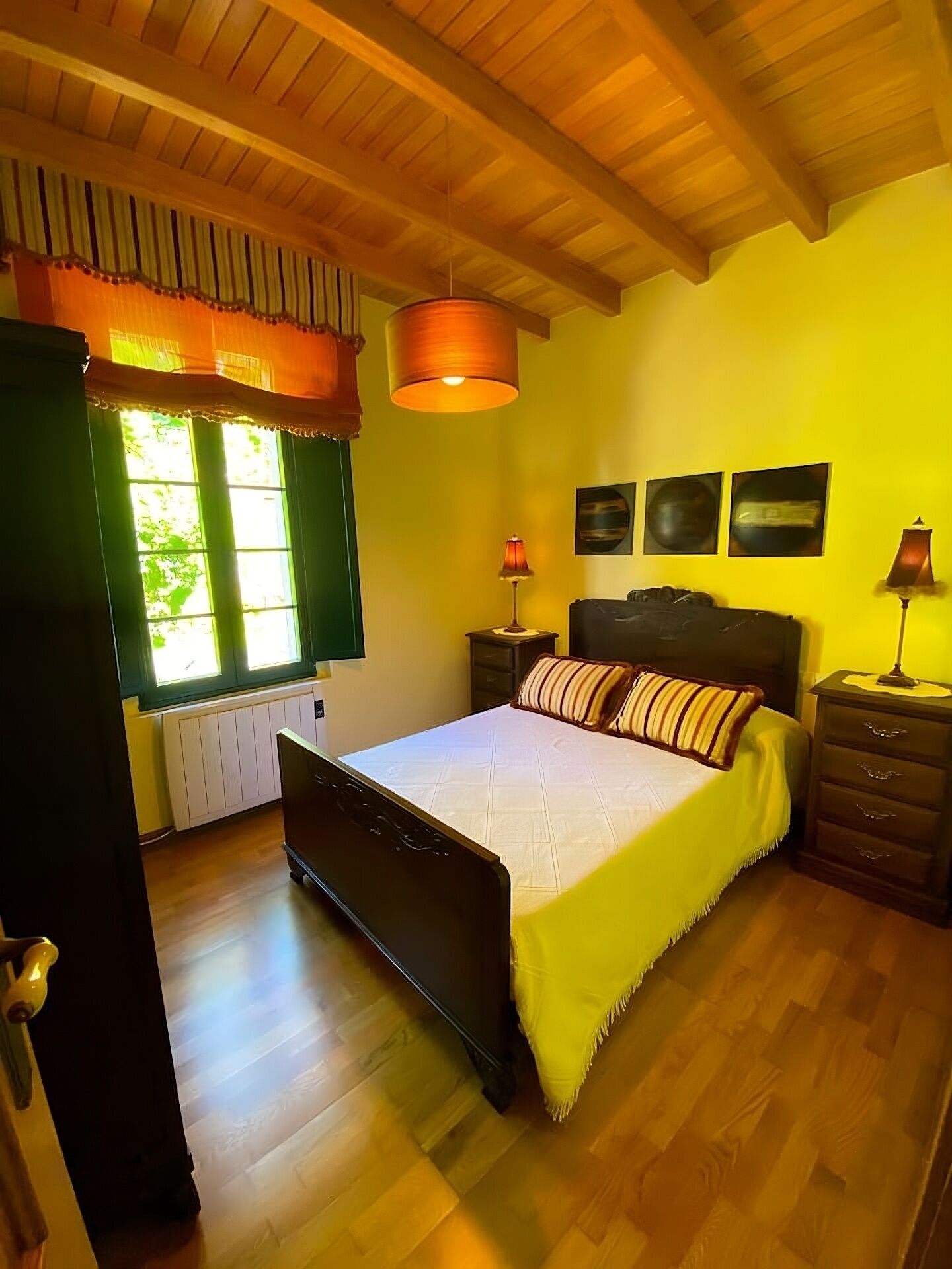 Une chambre à coucher avec un lit, une table de chevet, une lampe et une fenêtre avec des rideaux.