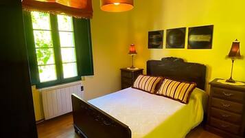 Une chambre à coucher avec un lit, une table de chevet, une lampe et une fenêtre avec des rideaux.