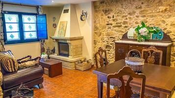 Un salon chaleureux avec une cheminée, un mur en pierre et un coin repas doté de meubles en bois.