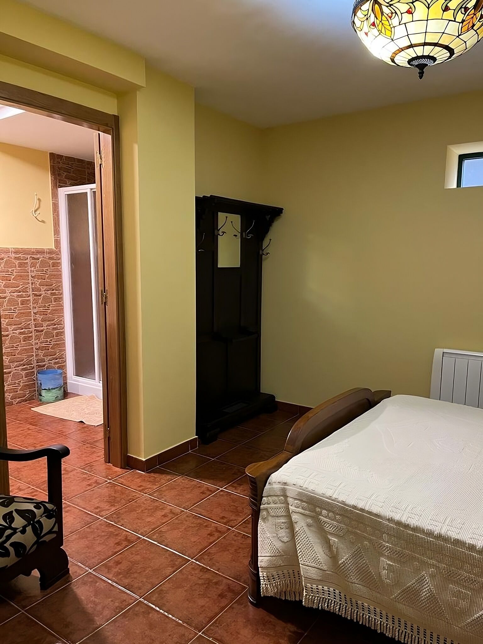 Une chambre à coucher comprenant un lit, une chaise, une armoire et une porte donnant sur un balcon.