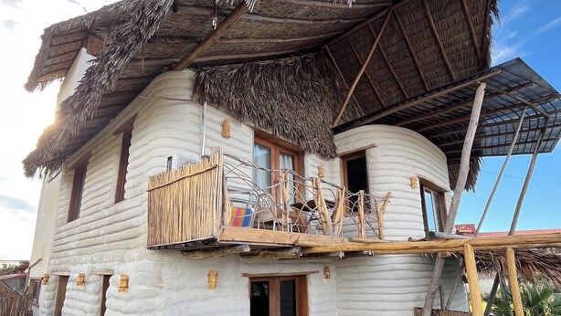 A rustic house with a thatched roof, a wooden balcony, and a small garden area with potted plants. - Solar Kaeté (Santo Amaro do Maranhão)