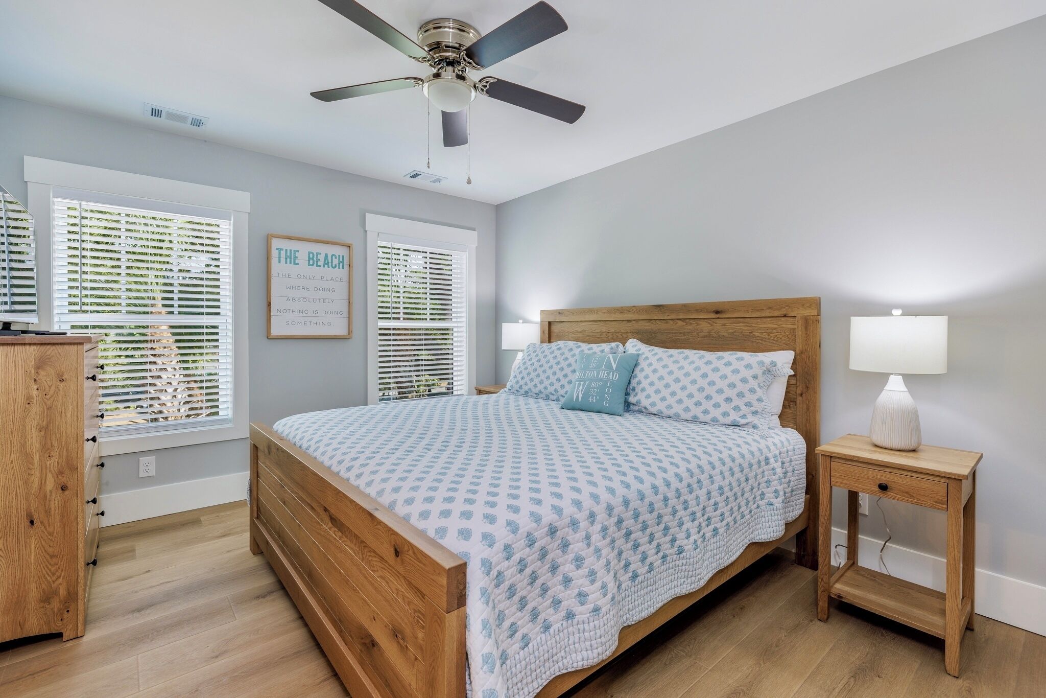 A bedroom with a wooden bed, a nightstand with a lamp, and a ceiling fan.