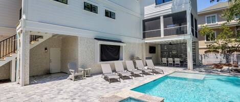 A two-story building with a swimming pool, outdoor seating, and a covered area with a fireplace.