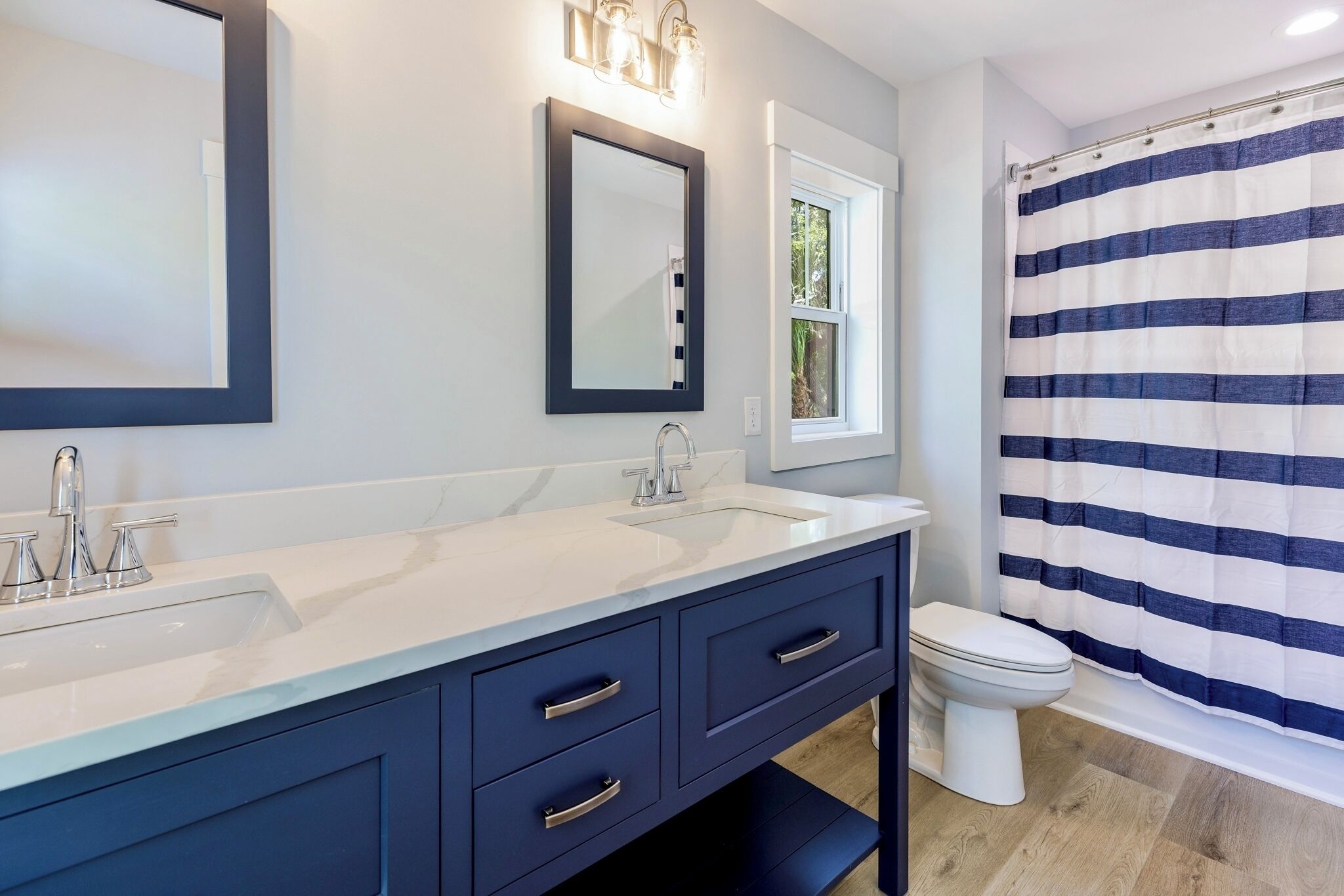 A bathroom with two sinks, a toilet, and a shower curtain.