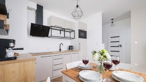 A modern kitchen with white cabinets, a wooden countertop, and a dining area with a wooden table set for two.