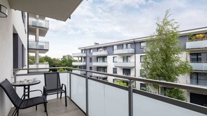 A balcony with a table and chairs, overlooking a residential building with multiple balconies.