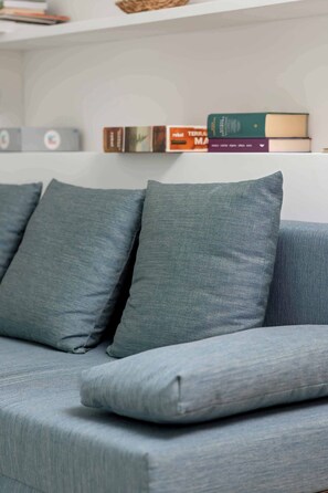 A grey sofa with matching cushions and a bookshelf with books and decorative items.