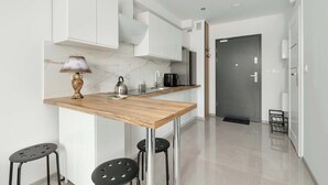 Una cocina moderna con armarios blancos, encimera de madera y dos taburetes negros.