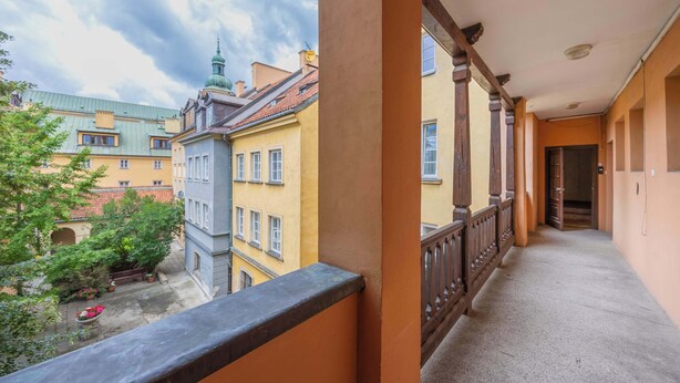 A corridor with a balcony overlooking a courtyard with buildings and trees. - Cozy Apartment in the Heart of the Old Town | Smart TV and Wi-Fi (Warszawa)