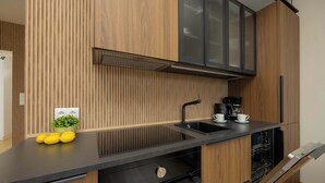 A modern kitchen with wooden paneling, a black countertop, and a built-in dishwasher. - Cozy Apartment in the Heart of the Old Town | Smart TV and Wi-Fi (Warszawa)
