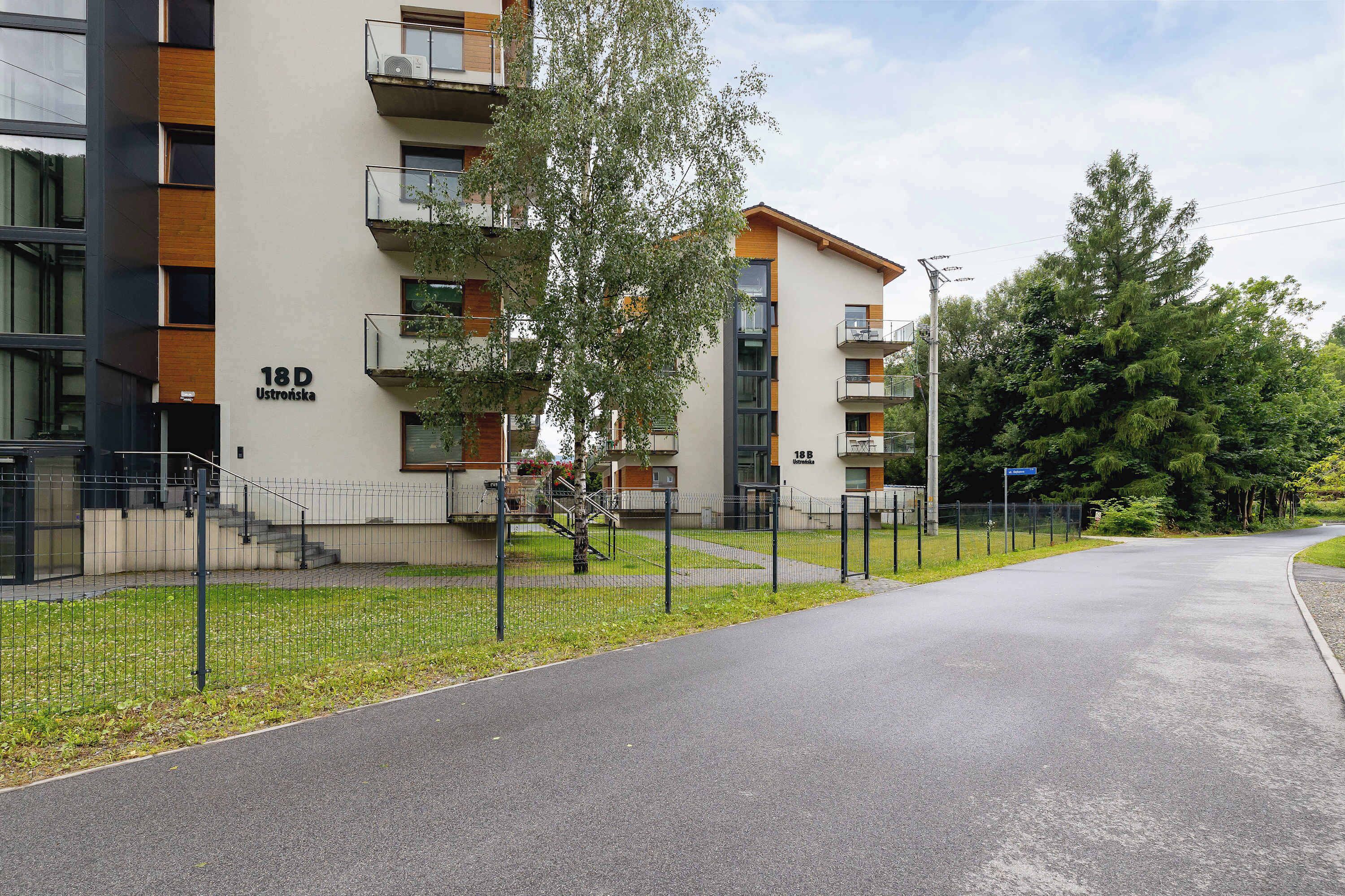 Ein modernes Mehrfamilienhaus mit Balkonen, einem verschlossenen Eingangsbereich und einem gepflegten Rasen.