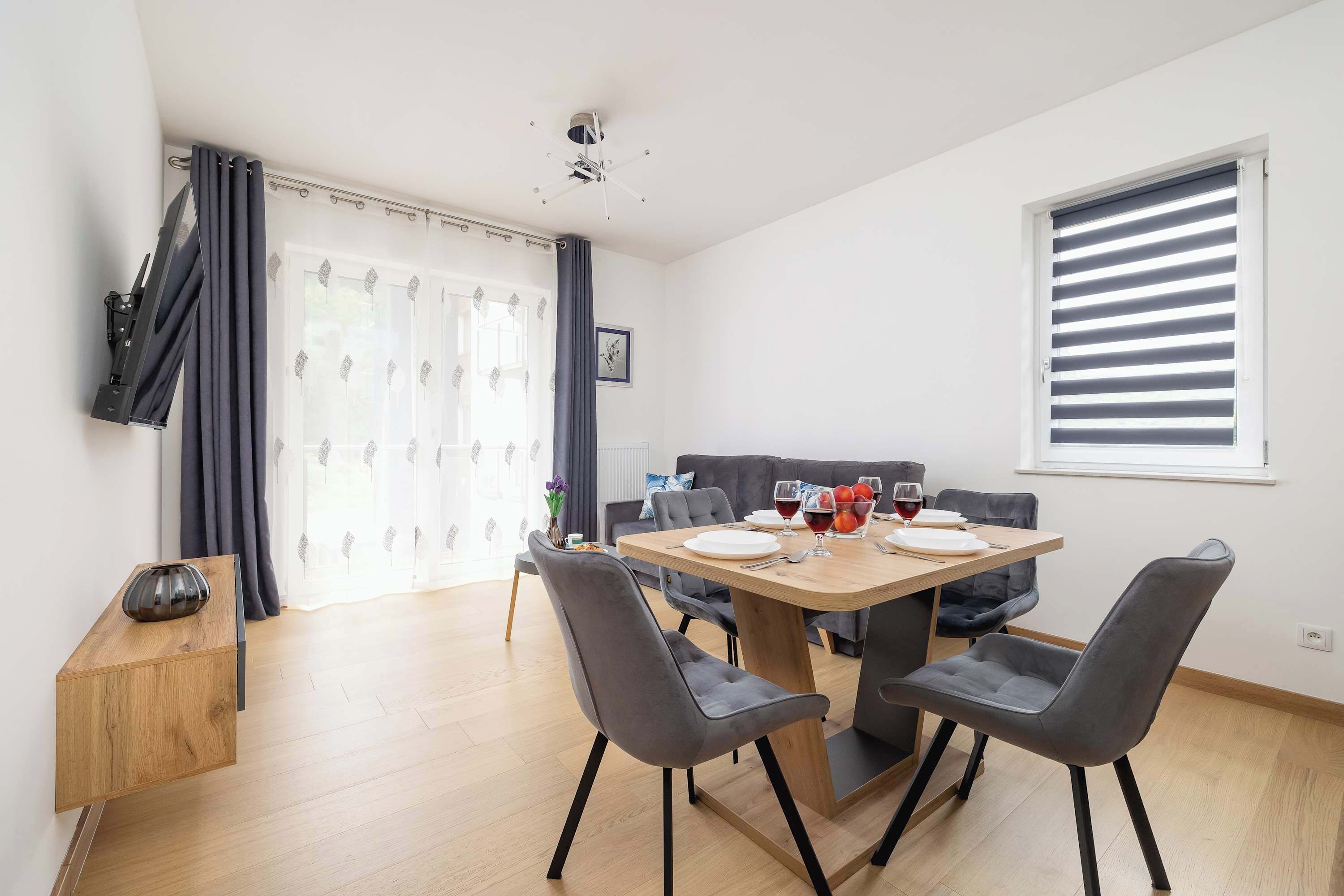 Een moderne eethoek met een houten tafel, grijs gestoffeerde stoelen en een houten dressoir.