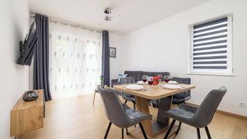 Een moderne eethoek met een houten tafel, grijs gestoffeerde stoelen en een houten dressoir.