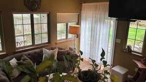 A living room with a sofa, a potted plant, a lamp, and a television.