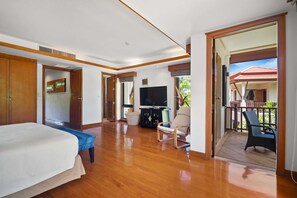 A spacious room with a bed, a TV, a seating area, and a balcony with outdoor furniture.