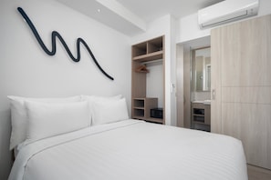 Une chambre d’hôtel moderne dotée d’un grand lit, d’une armoire, d’un dressing et d’un climatiseur fixé au mur.