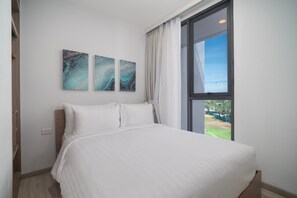 Quarto com uma cama grande, uma janela com cortinas e três obras de arte abstratas nas paredes.