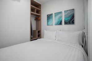 Une chambre à coucher avec un lit, une armoire en bois et deux tableaux abstraits accrochés au mur.