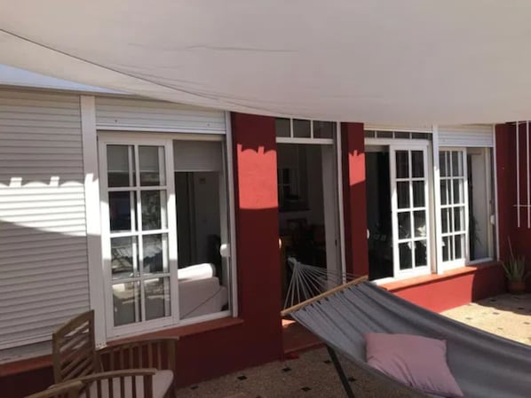 A room with a hammock, a chair, and a window with a view of the interior.