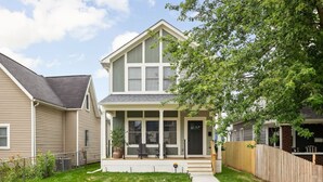 A two-story house with a front porch, a small garden, and a wooden fence. - Modern 3-bedroom home with fenced yard + easy parking (Indianapolis)