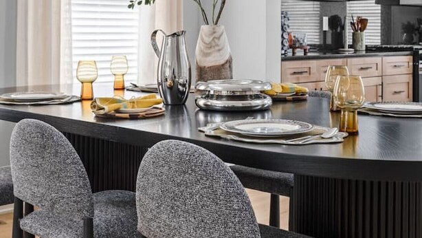 A modern kitchen with white cabinets, a black countertop, and a dining area with a black table and grey chairs. - Modern 3-bedroom home with fenced yard + easy parking (Indianapolis)