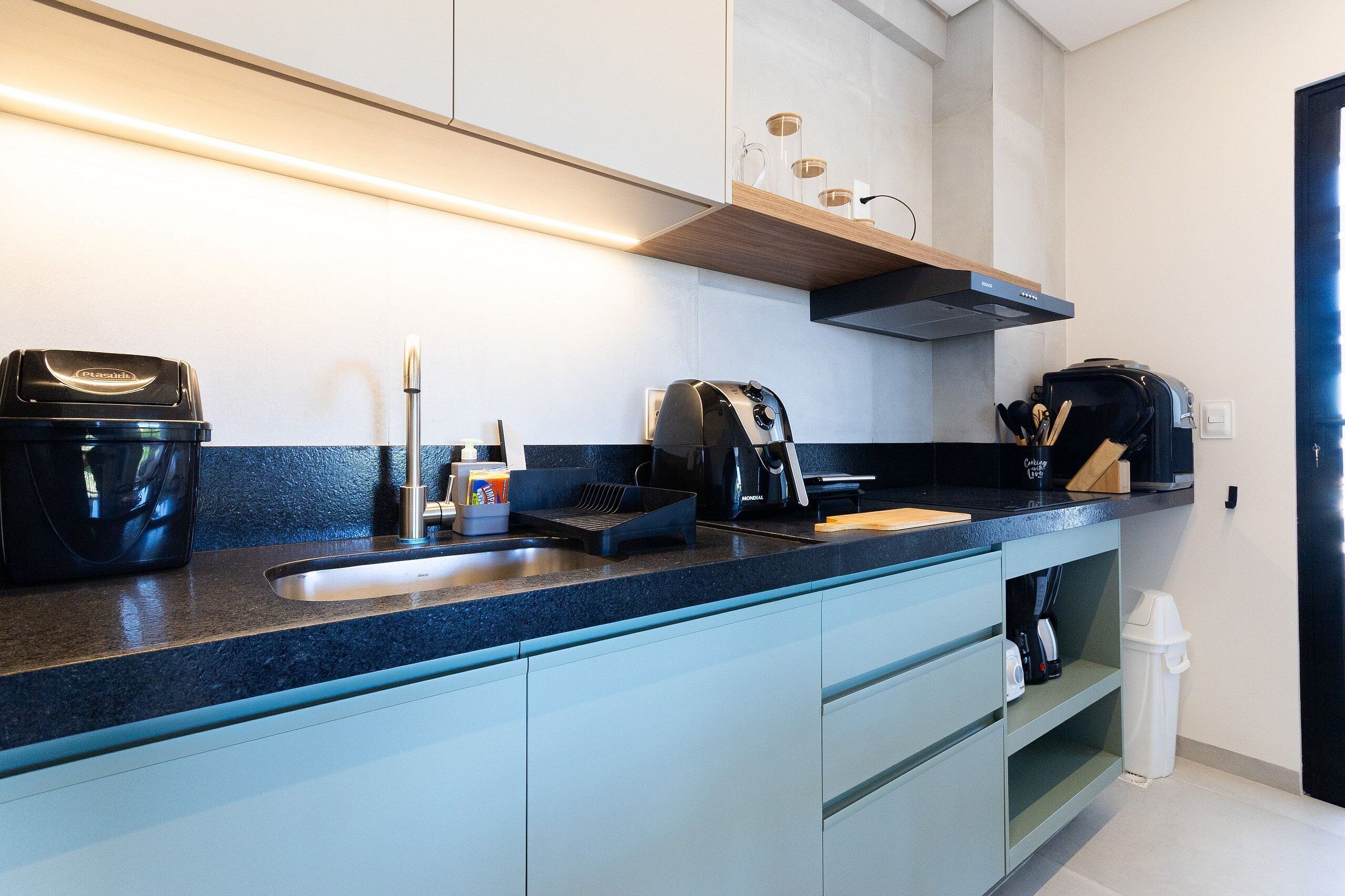 A modern kitchen with a built-in oven, a coffee maker, and a toaster. There is a sink and a countertop with a knife block.