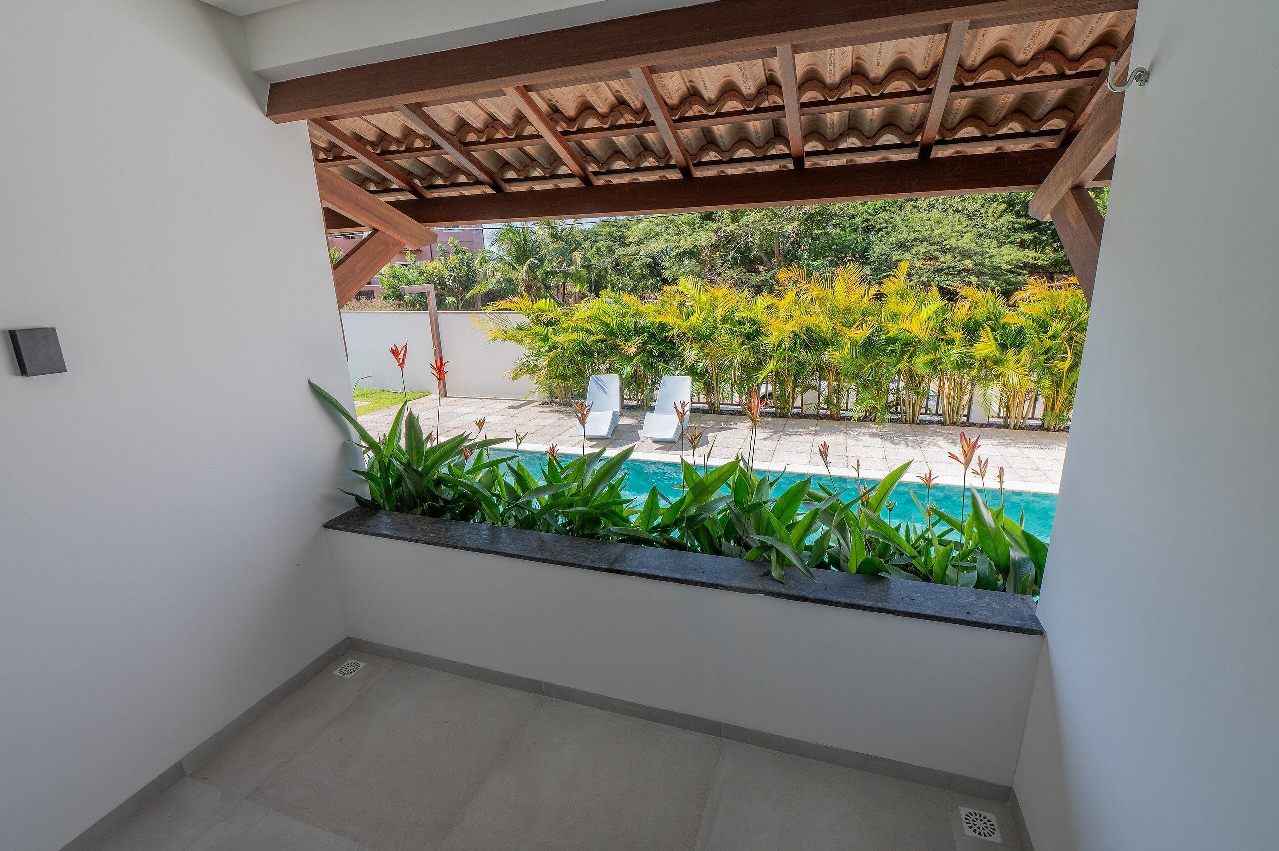 A balcony with a view of a swimming pool and tropical plants.