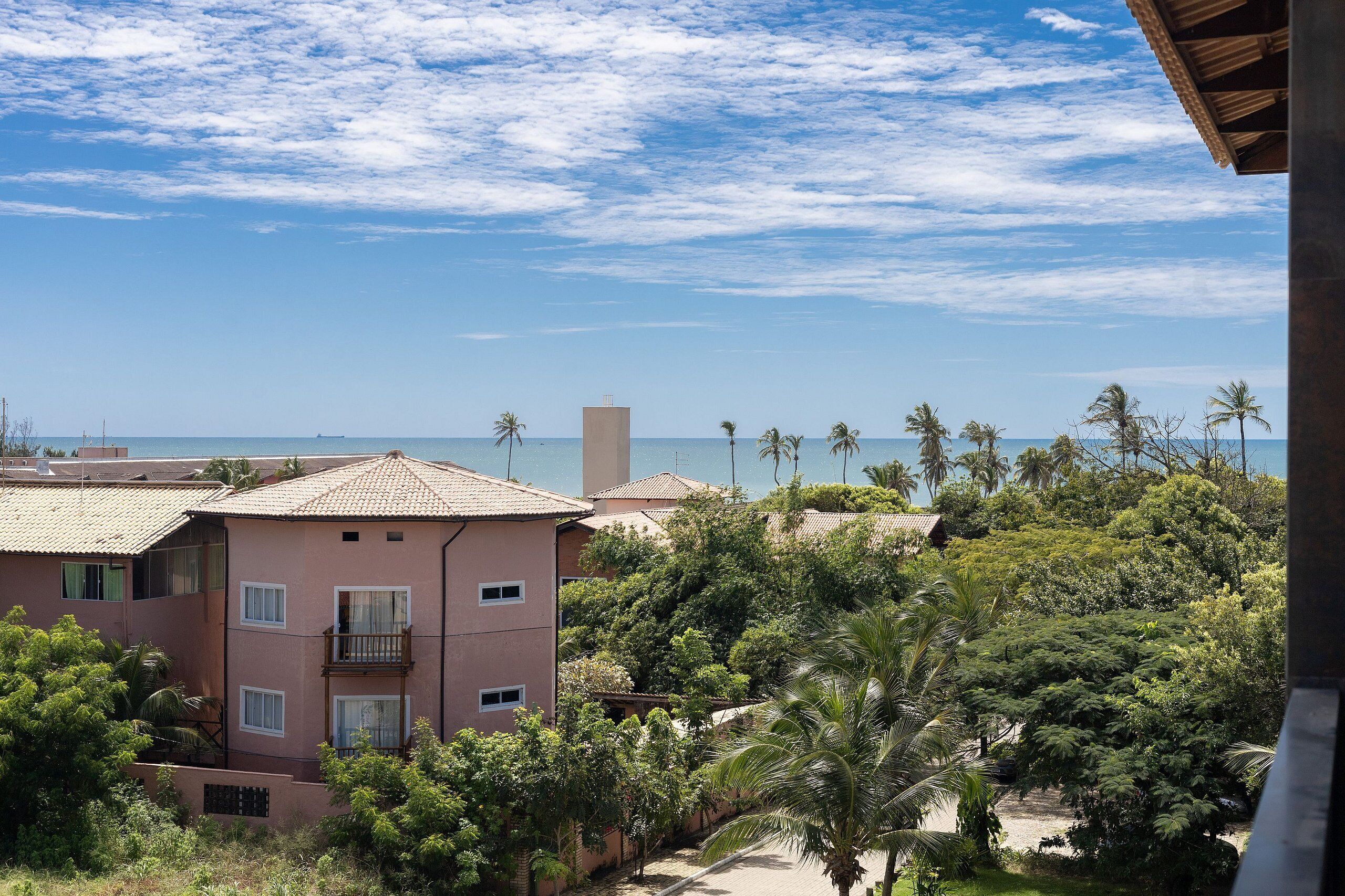 A multi-story building with balconies overlooking a beach and palm trees.