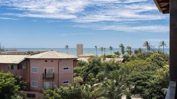 A multi-story building with balconies overlooking a beach and palm trees.