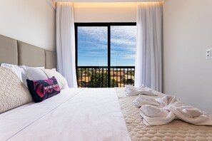 A hotel room with a bed, a view of the city, and a balcony with curtains.