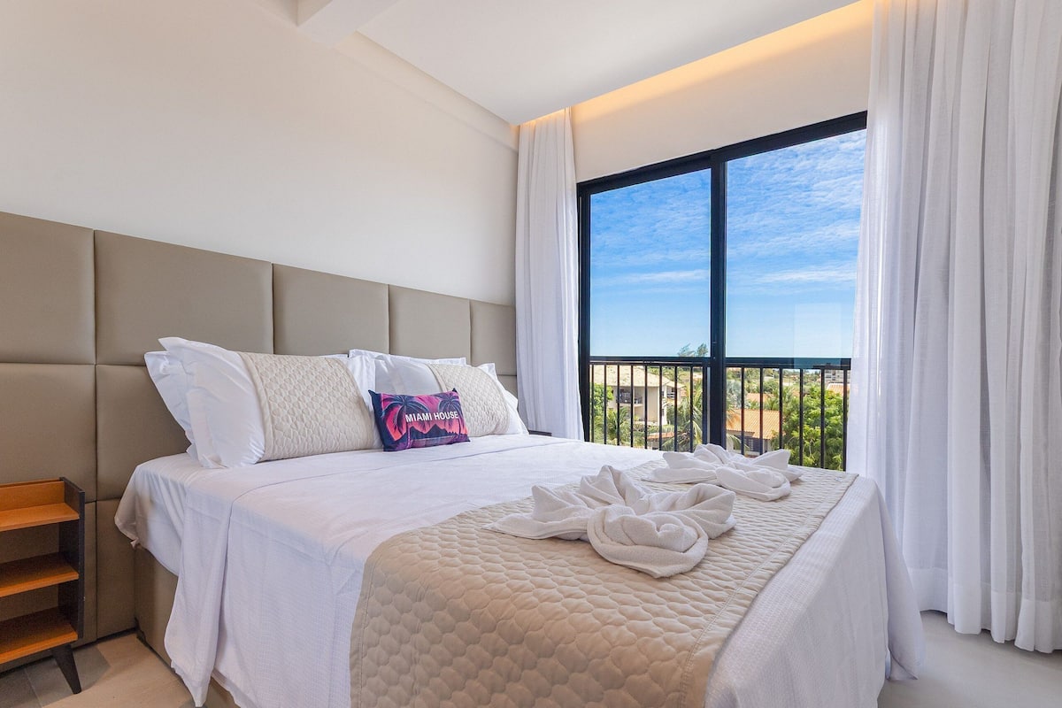 A hotel room with a large bed, a view of the outdoors, and a balcony.