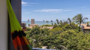 A view of a coastal area with palm trees, a beach, and buildings in the background.