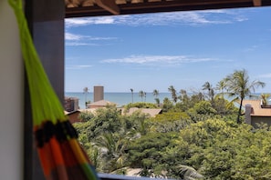 A view of a coastal area with palm trees, a beach, and buildings in the background.