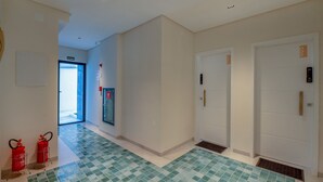 A hallway with a tiled floor, a fire extinguisher, and a door with a keypad lock. - Miami House Cumbuco by Carpediem (Caucaia)