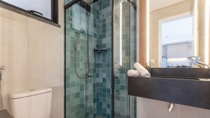 A modern bathroom with a glass-enclosed shower, a toilet, and a sink with a mirror above it. - Miami House Cumbuco by Carpediem (Caucaia)