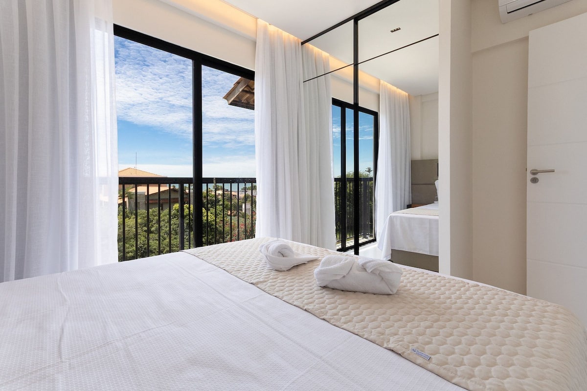 A hotel room with a large bed, a view of the outdoors, and a balcony.