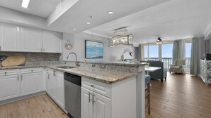Una cocina moderna con armarios blancos, encimeras de granito y una isla grande.