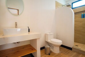 A bathroom with a white sink, toilet, and a small trash can.