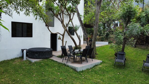 A patio area with a round table and chairs, a small round table with a black tablecloth, and a black inflatable pool.