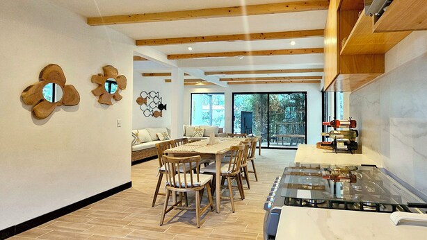 A spacious kitchen with wooden beams, a dining area with a large table and chairs, and a modern stove.