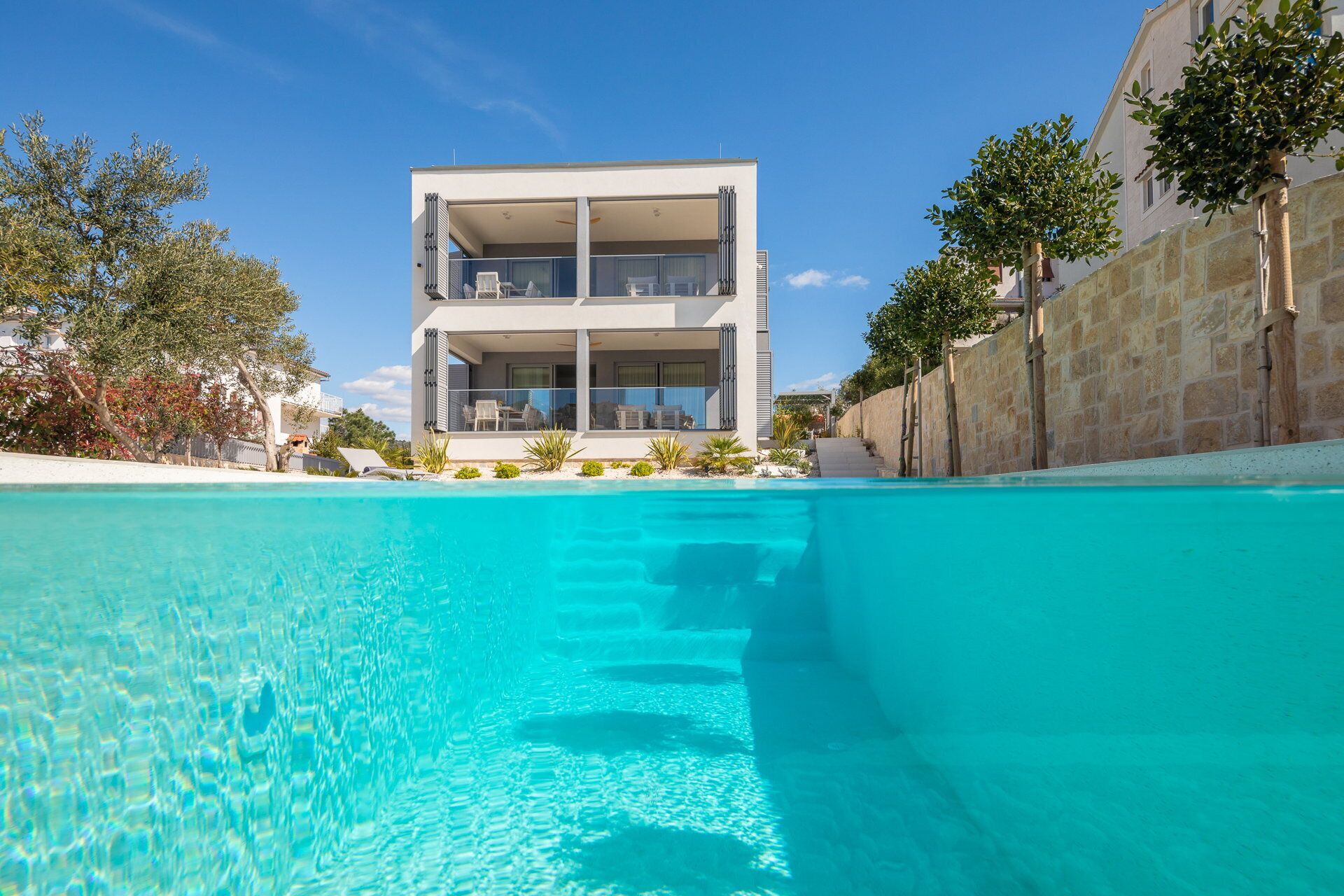 A modern two-story building with a pool in the foreground.