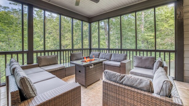 A covered outdoor seating area with wicker furniture and a fire feature. - Ultimate Creek Retreat- private 250 ft waterfront - Hot Tub, Sauna, Game Room (Epworth)