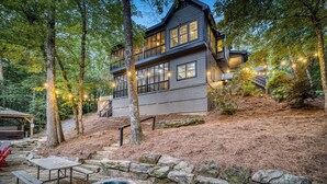 A modern two-story cabin with a stone fire pit and picnic tables in a forest setting. - Ultimate Creek Retreat- private 250 ft waterfront - Hot Tub, Sauna, Game Room (Epworth)