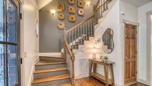 A staircase with wooden steps and a wooden railing, a console table with a lamp, and a door with a mirror above it. - Ultimate Creek Retreat- private 250 ft waterfront - Hot Tub, Sauna, Game Room (Epworth)