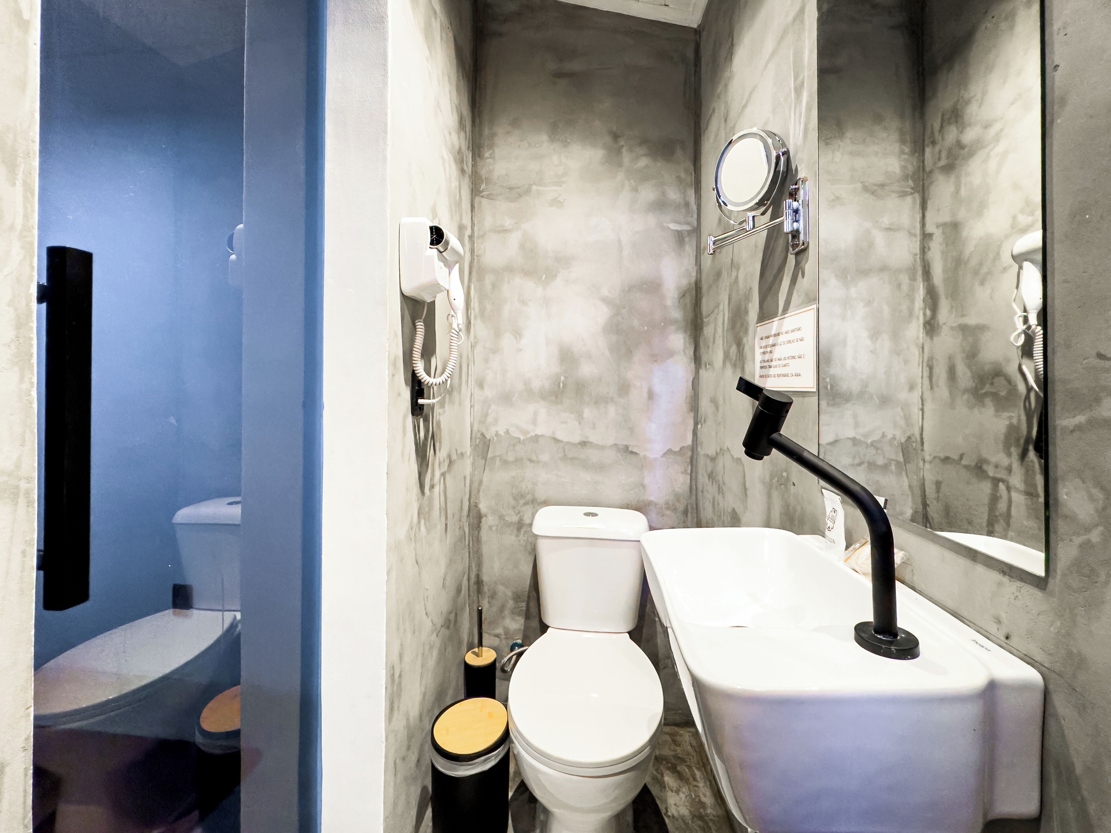 A compact bathroom with a toilet, sink, and mirror.