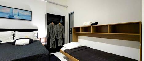 A modern hotel room with two single beds, a wardrobe, and a painting on the wall.