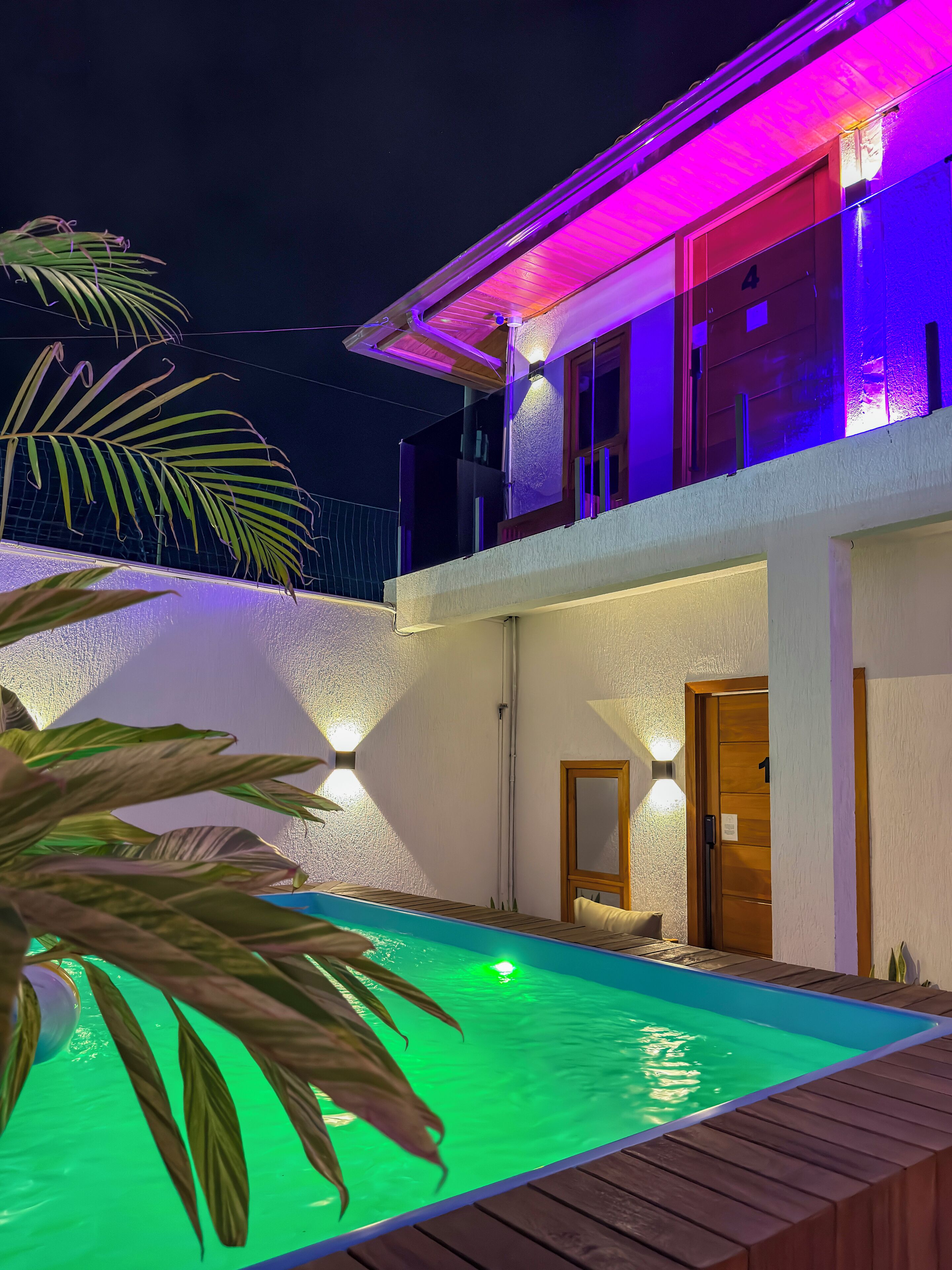Un edificio de dos pisos con piscina, un balcón y una puerta marcada con el número 1.