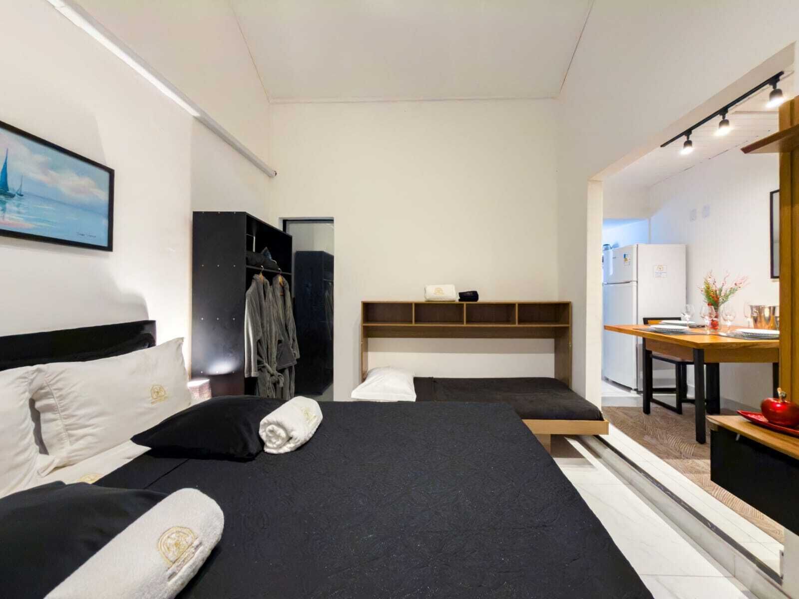 Una habitación de hotel moderna con dos camas, un armario, una kitchenette pequeña y una zona de comedor.